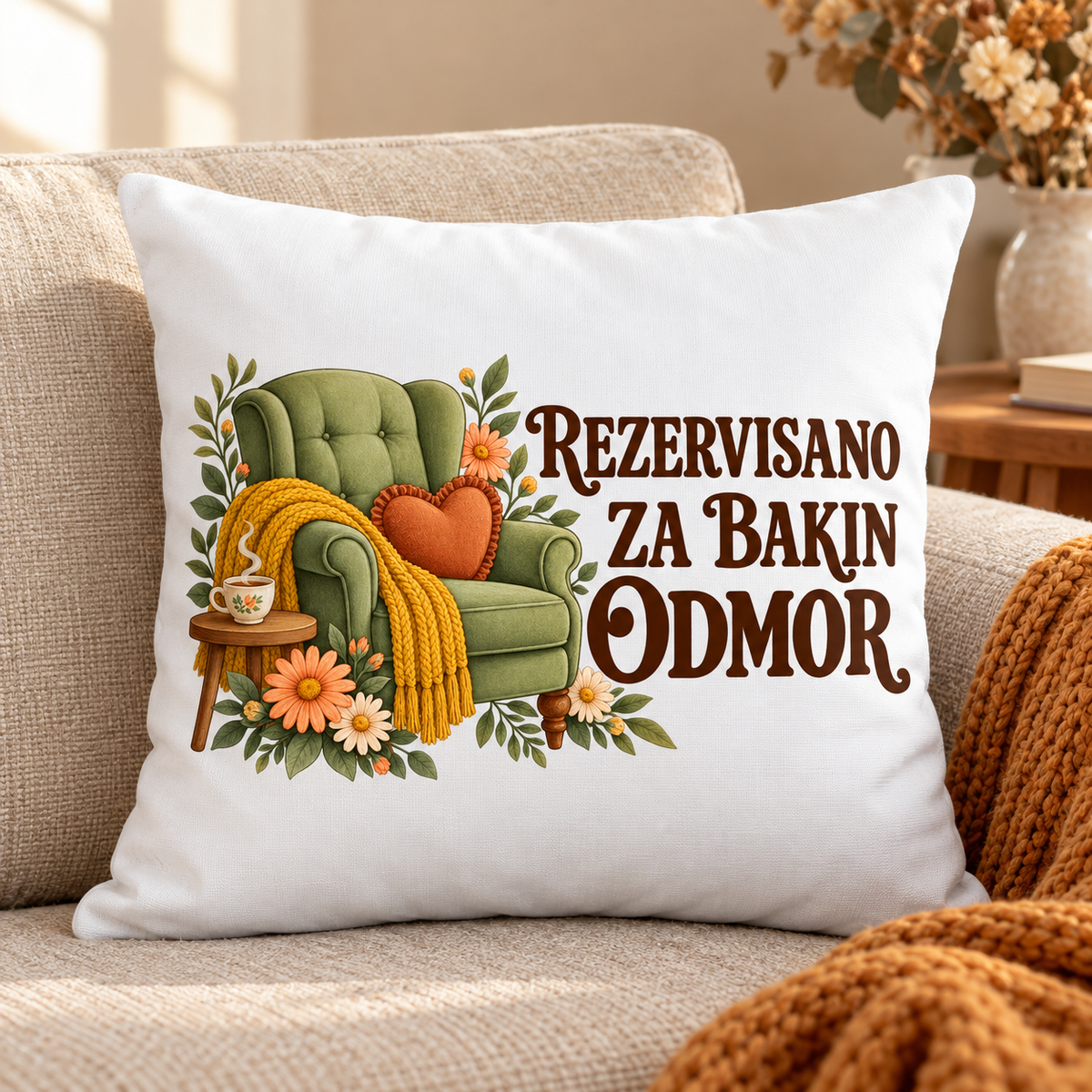 Beli jastuk sa zelenom foteljom, žutim prekrivačem i natpisom Rezervisano za bakin odmor na bež sofi